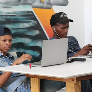 Teenage boys in a classroom setting working on laptops.