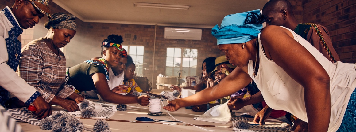 A group of workings around a table working together with textiles.