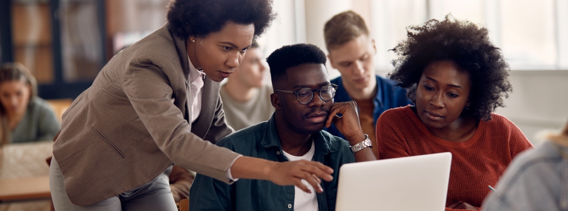 Young professionals being trained while being shown material on a laptop screen.