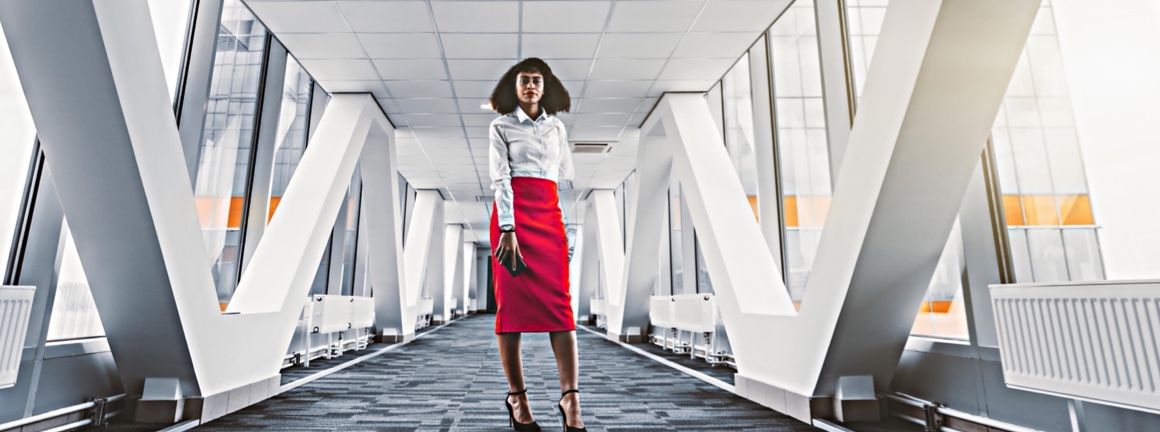 Young professional women standing boldly in office corridor.